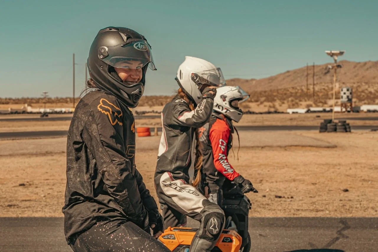 Lauren Ford, nearest the camera in a Fox jersey and Arai helmet, with two other women riders on the grid at a desert circuit