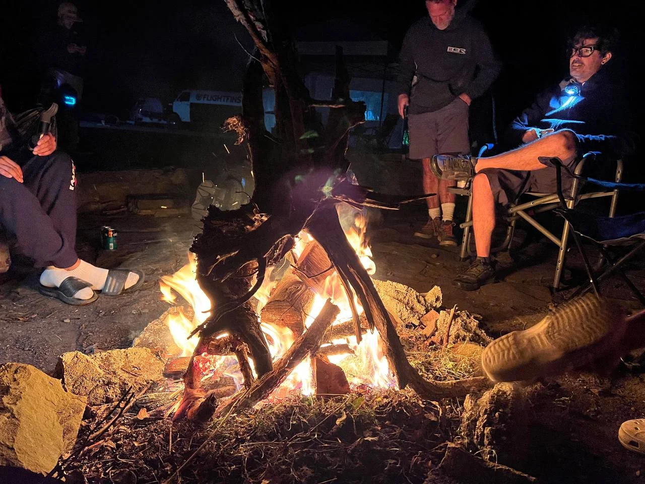 Riders gathered around the campfire at night at Camp Shred